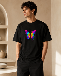 Man wearing a black t-shirt with a colorful butterfly design in a neutral setting