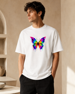 Man wearing a white t-shirt with a colorful butterfly design against a beige wall.