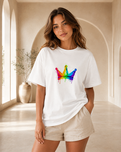 Person wearing a white t-shirt with a colorful crown design in a bright room.