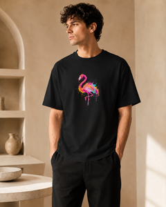 Man wearing a black t-shirt with a colorful flamingo design in a neutral setting.