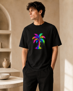 Man wearing a black t-shirt with a colorful palm tree design in a neutral setting.