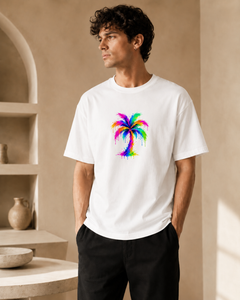 Man wearing a white t-shirt with a colorful palm tree design in a neutral setting.
