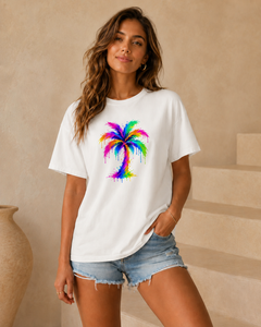 Woman wearing a white t-shirt with a colorful palm tree design in a neutral setting.