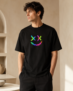 Man wearing a black t-shirt with a colorful smiley face design in a neutral setting