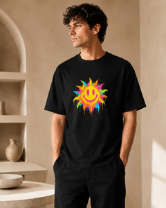 Man wearing a black t-shirt with a colorful sun design in a room with beige walls and shelves.
